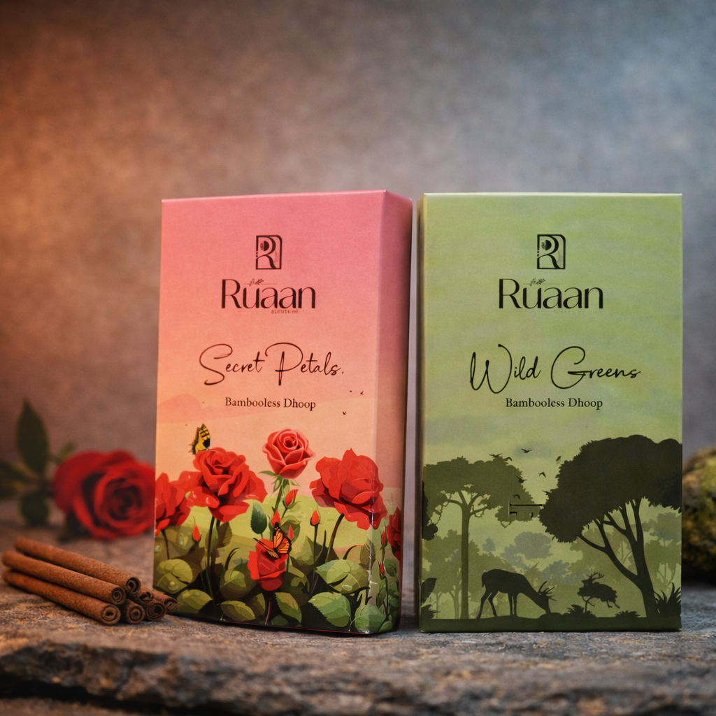 Two Ráaan incense boxes, one pink with roses and one green with trees, on a stone surface.
